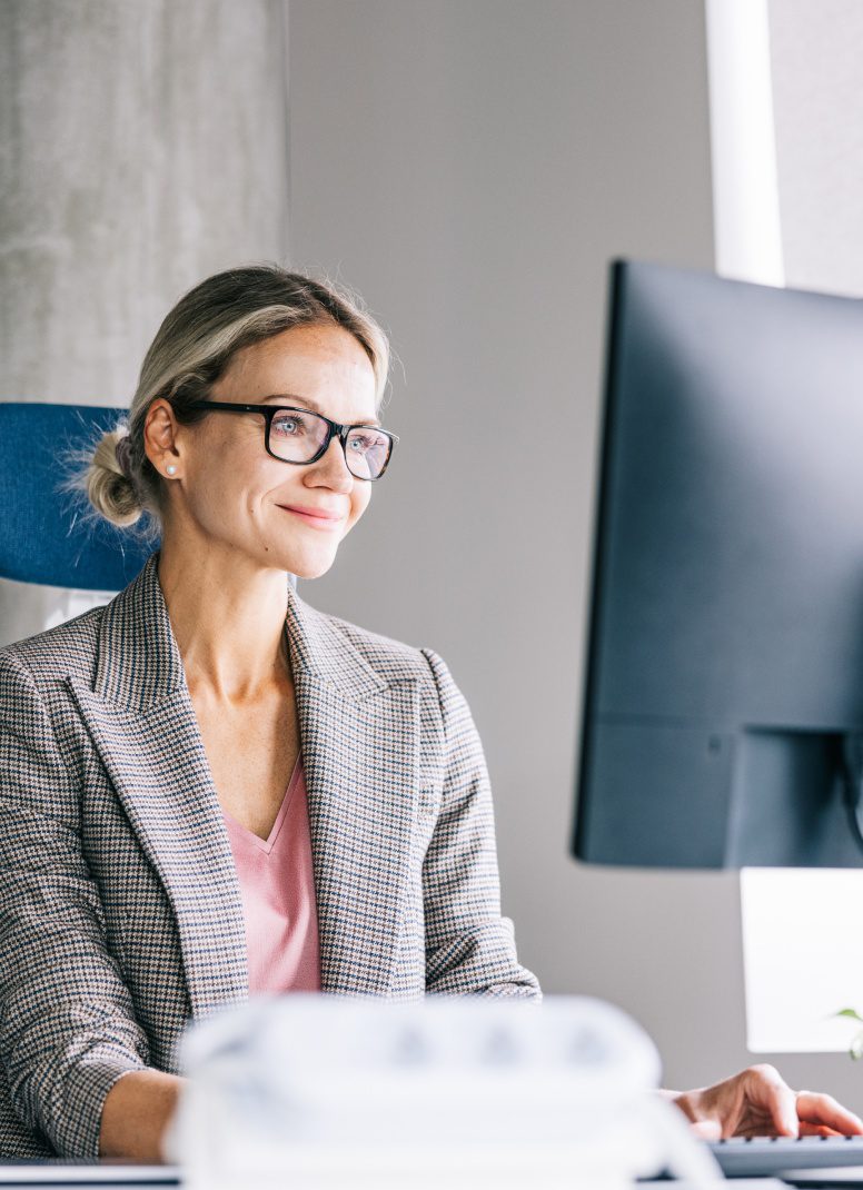 Smiling professional woman working at a computer in an office.