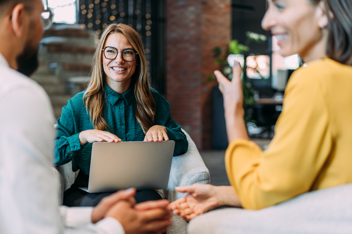 Three financial professionals collaboratively reviewing website performance on laptop representing personalized strategic approach to custom RIA website design and optimization